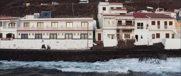 Aerial view of a man seated on the stairs of a house at a coastal village alt