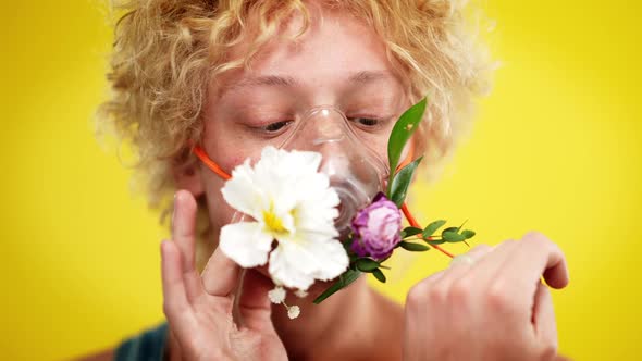 Closeup of Young Androgynous Man in Mask with Flowers Looking at Camera with Serious Facial alt