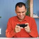 Happy Man Is Playing Video Game at Home Office Using Modern Smartphone - VideoHive Item for Sale