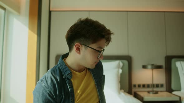 asian adult male traveller sit relax on hotel bed vacation concept alt