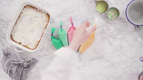 Flat lay. Piping rosettes with Italian buttercream frosting on top of sheet cake. alt