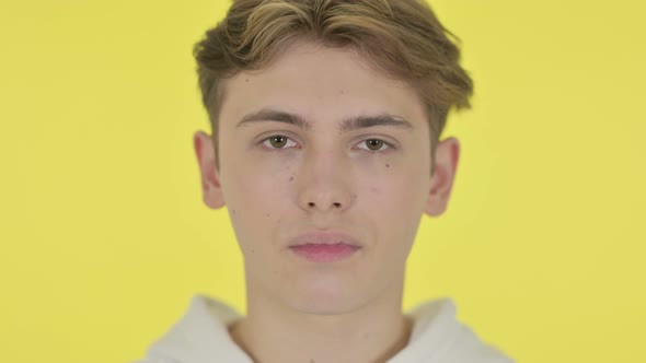 Close Up of Serious Young Man Yellow Background alt