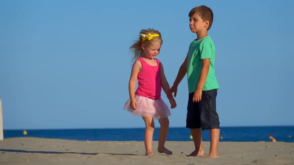 Little Boy and Girl in the Pink Skirt are Playing on the Beach, Stock Footage