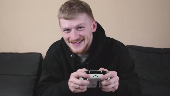 Joyful Guy Playing Video Games on a Console with a Gamepad and Headset