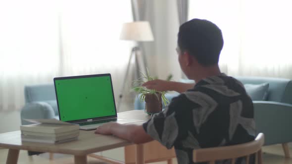 Asia Boy Sitting At His Desk Learning Online On A Laptop With Green Mock-Up Screen At Home alt