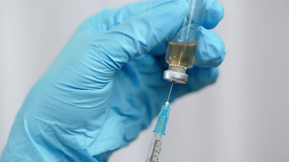Nurse or Doctor hands filling the syringe with vaccine. Focus is on syringe.