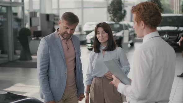 Man Shaking Hand of Car Salesman in Dealership alt