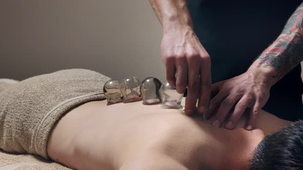 Cupping massage. Young man enjoying back and shouders massage in spa alt