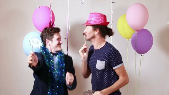 Two happy men dancing with props in photo booth alt