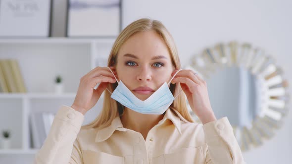 Young attractive woman putting on a medical blue mask. Beautiful girl with medical mask alt
