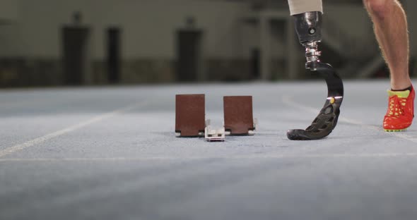 Low section of caucasian disabled male athlete with prosthetic leg getting ready to start a run alt