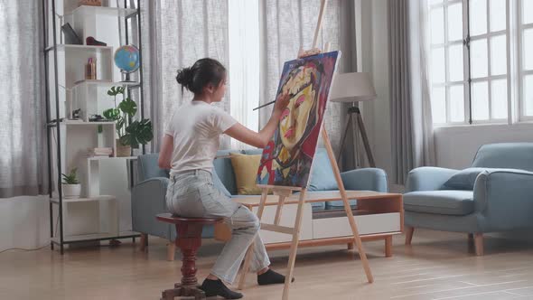 Asian Artist Girl Coming To Sit And Holding Paintbrush Painting A Girl's Hair On The Canvas alt