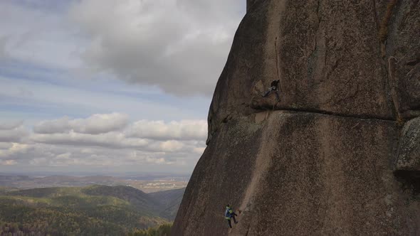 Two Men Climb a Vertical Rock Wall. Mountaineering Partner Insurance.