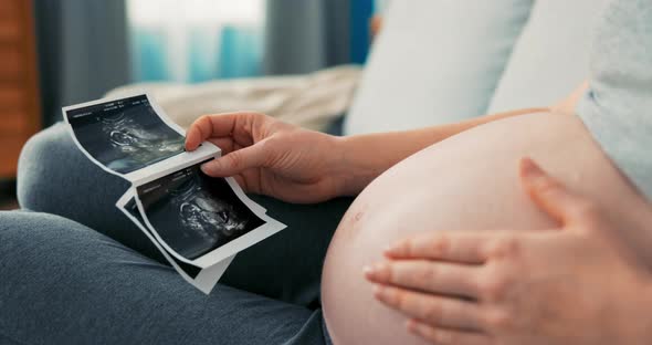 Shot From Above with a View of a Pregnant Lady Sitting on Sofa Wearing Sweatpants alt
