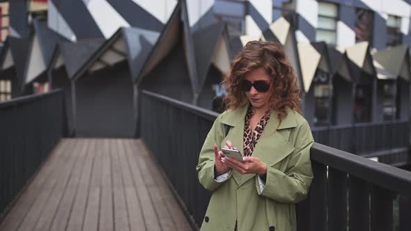 A Young Stylish Woman with a Smartphone in the Art Space
