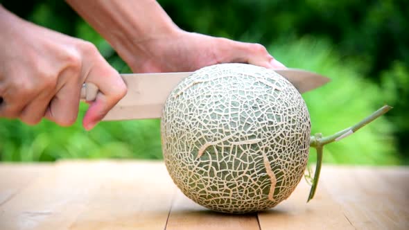 The man use knife split the green melon  alt