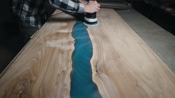 The Carpenter Processes the Surface of a Wooden Tabletop with a Grinder alt