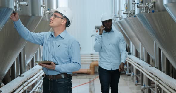 Two Industry Engineers Walk in Factory Use Tablet and Discuss Work alt