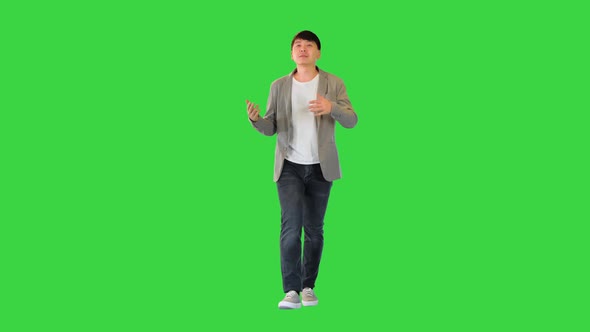 Young Asian Man Walks Telling Something on a Green Screen Chroma Key