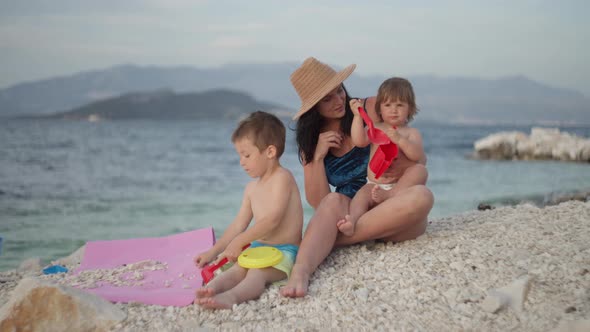 Mom with Children Playing By the Sea on Summer Vacation alt