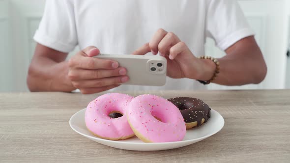 Unrecognizable Man Photographs Donuts on a Smartphone alt