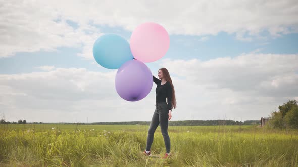 Happy Girl with Big Multicolored Balloons Posing on the Field alt