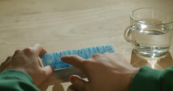 Man's Hands Taking Pills From Plastic Pill Organizer Box