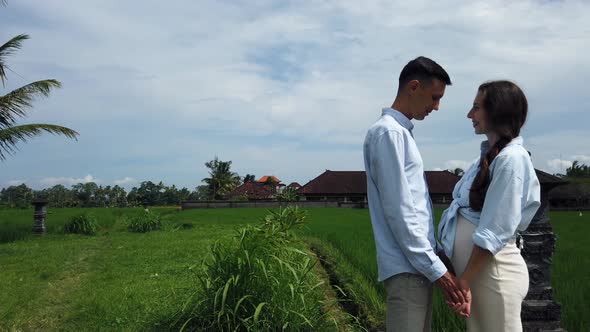 Romantic couple man and pregnant woman hugging and look on each other in rice fields Bali Indonesia