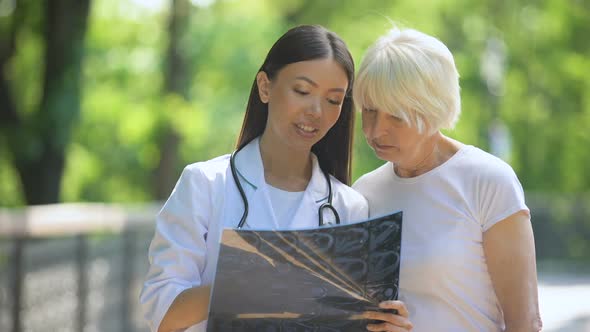 Nurse Showing Elderly Woman Joint X-Ray Examination Result, Smiling at Camera alt
