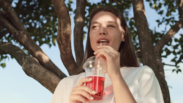 Woman Having Soft Drink by Tree alt