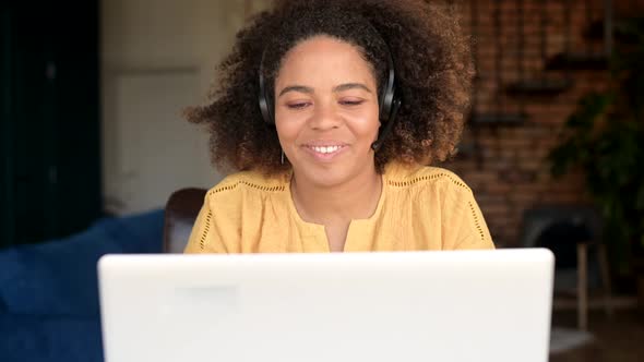 Cheerful AfricanAmerican Woman in Headset Talking Online with Colleagues or Customers alt