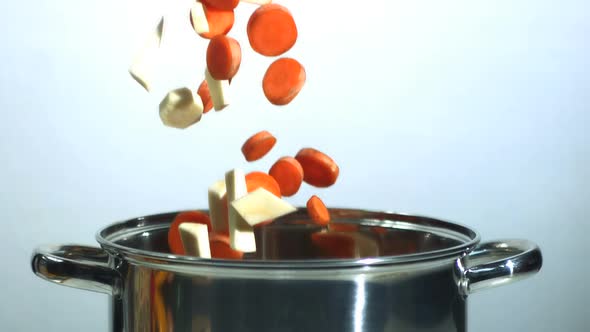 Chopped carrot and parsnip falling into saucepan alt