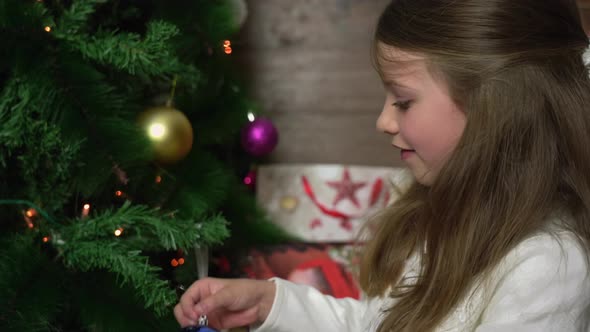 Pretty happy girl hangs Christmas tree decoration