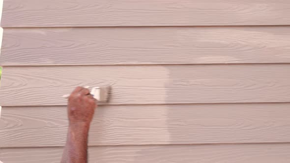 Builder worker painting woodwork brown color on cornice or moulding exterior outside home alt