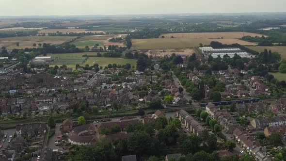 Tracking aerial shot of a commuter train passing through the town of Faversham, Kent, UK alt
