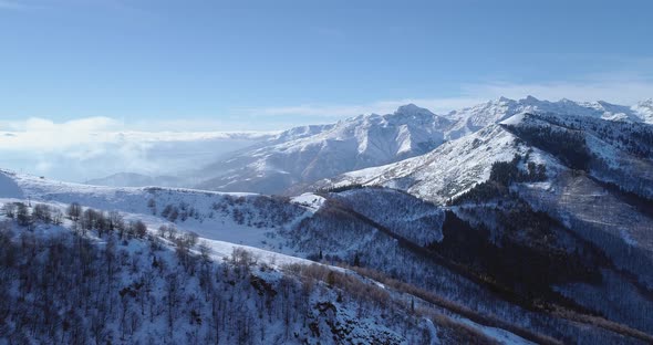 Forward Aerial on White Snow Mountain Peak in Winter Revealing Valley