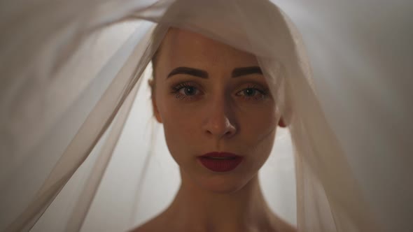 Headshot of Artistic Beautiful Sensual Woman Covering Face with Transparent Beige Scarf Moving Hands alt