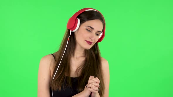 Cheerful Girl Dancing and Enjoys Music in Big Red Headphones. Green Screen alt