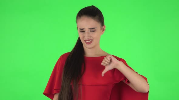 Portrait of Pretty Young Unhappy Woman Is Showing Thumbs Down Gesture. Green Screen alt