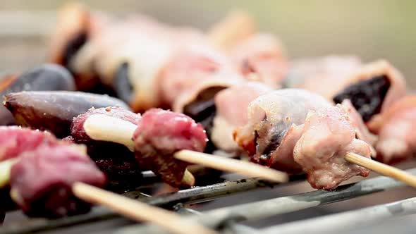 Beef and fig and prosciutto and prune kebabs sizzling on grill