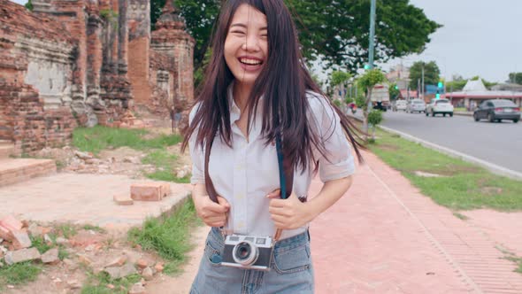 Asian backpacker blogger woman tourist hold camera walk and run lead with happy smile excited trave