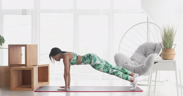 Slim black woman standing in plank position. alt