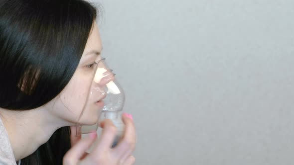 Use Nebulizer and Inhaler for the Treatment. Closeup Woman's Face Inhaling Through Inhaler Mask