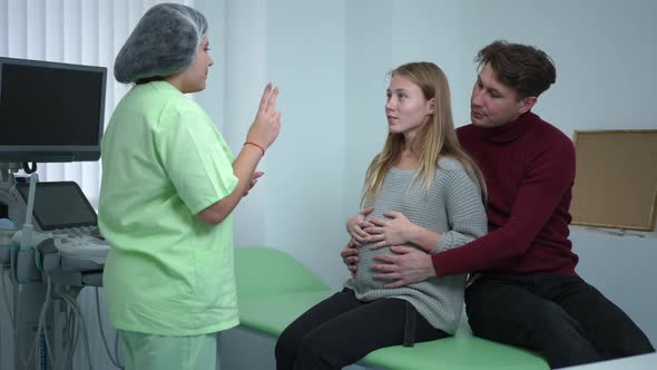 Young Pregnant Wife with Husband Learning Breathing As Doctor Gesturing Showing Exercise alt