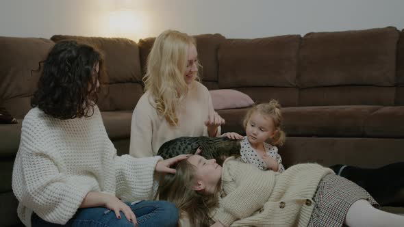 Mother with Daughters at Home Stroking Cat on Floor By Sofa Rbbro Young Woman Bonding with Children alt