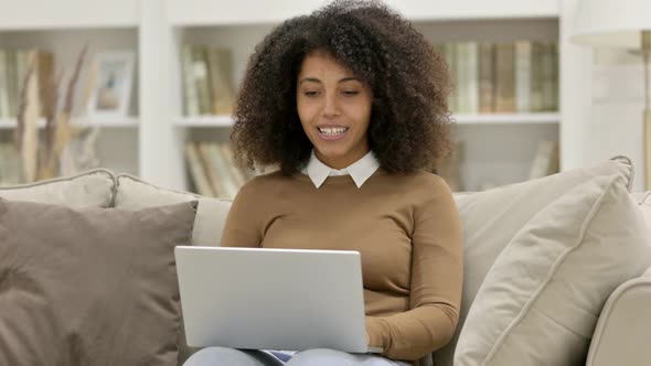 Online Video Chat on Laptop By Young African Woman on Sofa alt