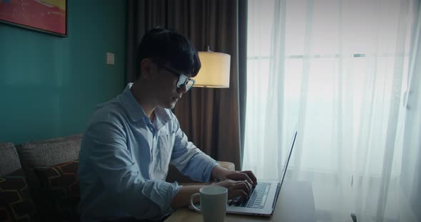 Young Attractive Asian Vietnam Man Busy Work Computer or Smart Tablet on Laptop at Home in Freelance alt