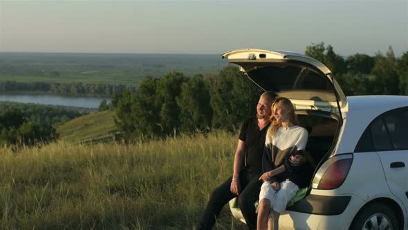 romantic couple sitting in the trunk of a car at the cliff with a beautiful view