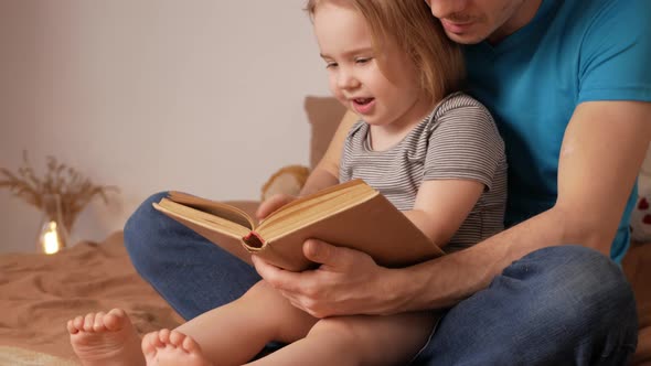 Dad and Daughter Read Book on Bed in Bedroom Process of Learning and Upbringing Little Girl Child