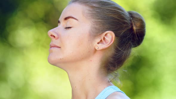 Lady with blonde hair bun relaxes after exercises and meditates breathing alt